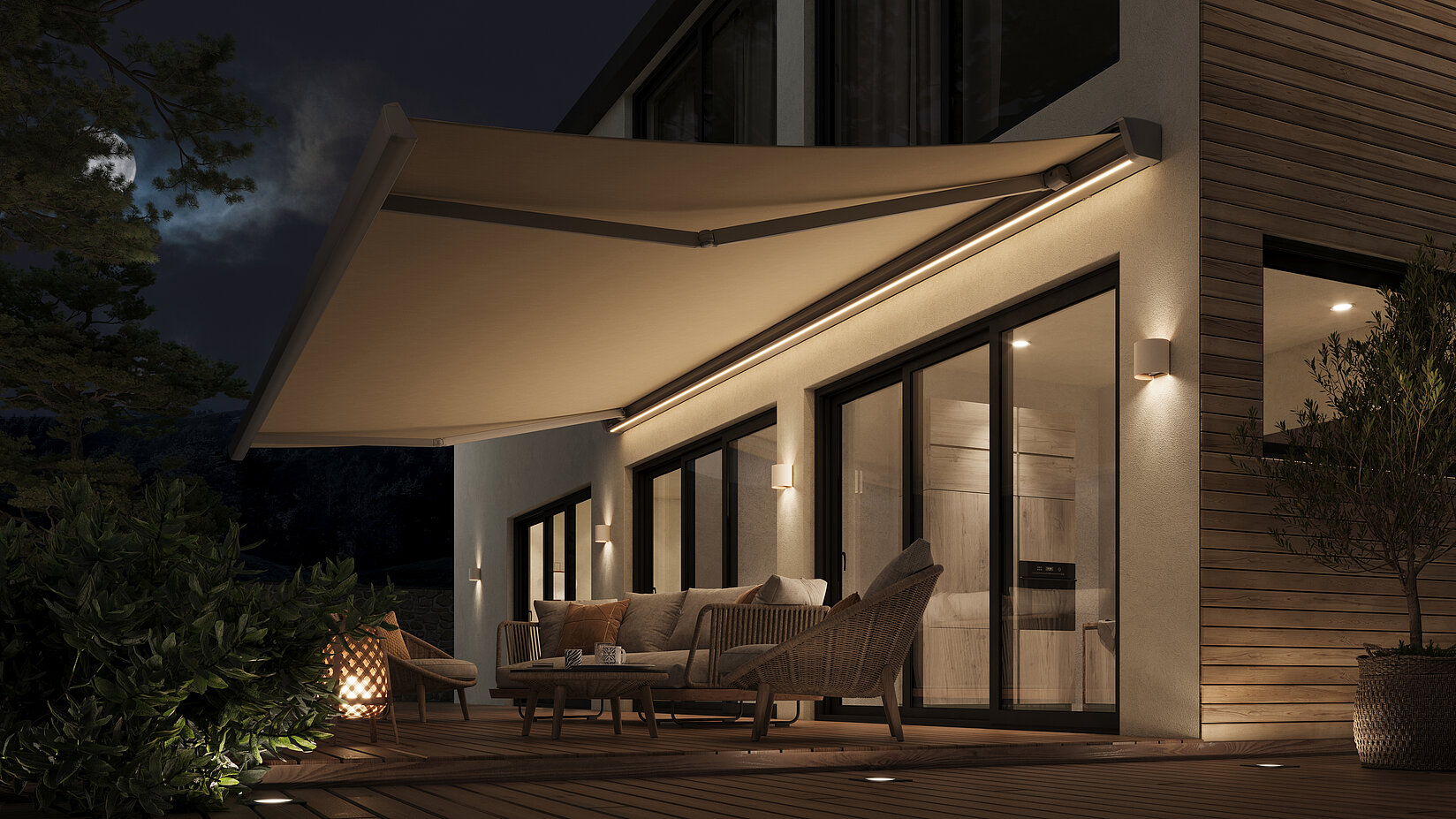 Beige Gelenkarmmarkise mit integrierter Beleuchtung über Terrasse eines Hauses bei Abenddämmerung.
